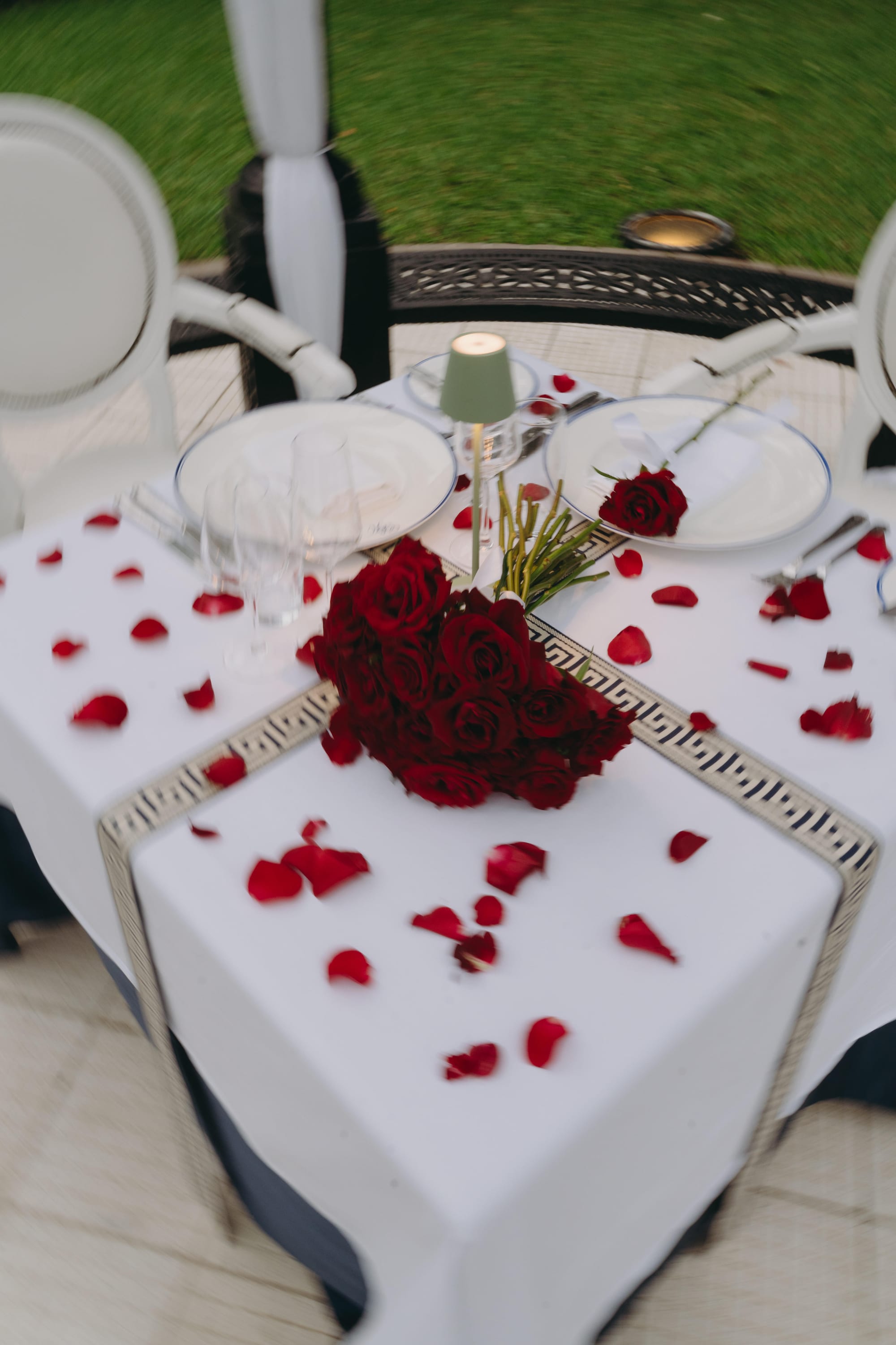 A bouquet of red roses and scattered petals on the wedding table